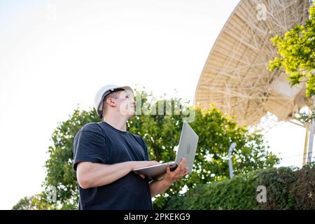 Engineer testing earth based astronomical radio telescope use laptop ...