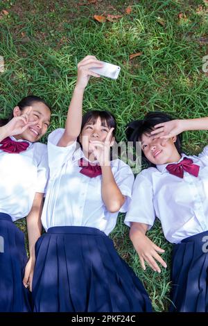 Junior high school students taking a picture lying on the grass Stock Photo