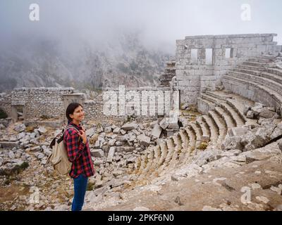 Autumn walk , woman looking at the ancient amphitheatre in city Termessos Ancient City, Turkey. Turkeys most outstanding archaeological sites and one Stock Photo