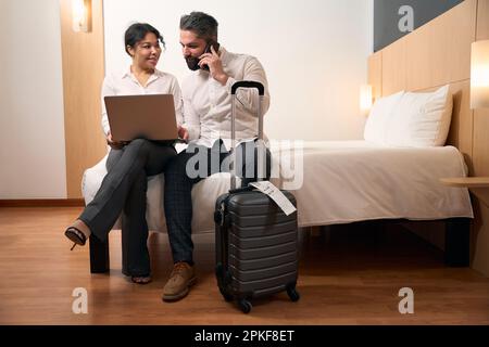 Couple with portable computer sitting in hotel room Stock Photo