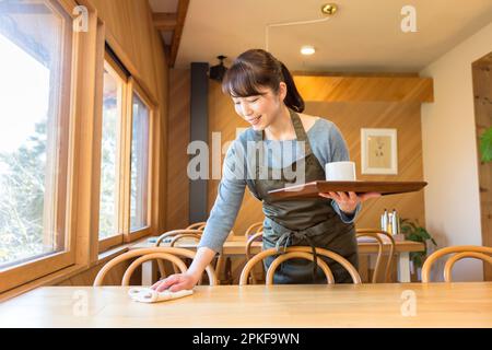 A female waitress clearing a table Stock Photo