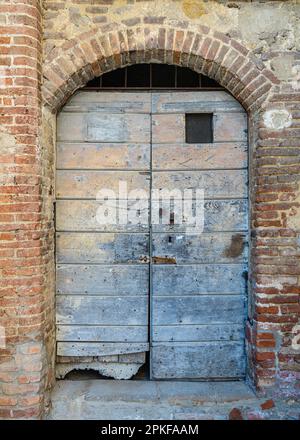 Brick archway with dilapidated blue and green doors in Tuscany Stock Photo