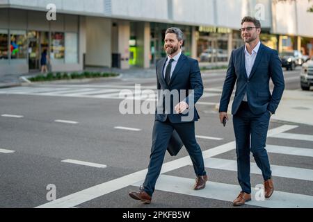 Businessmen couple walking across the crosswalk on american city street outdoor. Cheerful middle eastern businessman walking by street. Portrait of Stock Photo
