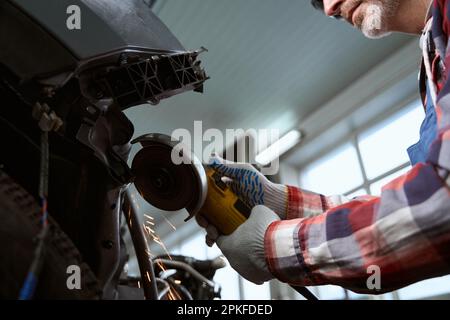 Car mechanic in goggles cuts off pneumatic cutter part Stock Photo