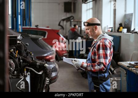 Man stands in workshop with working documentation in his hands Stock Photo