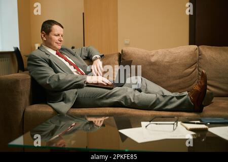 Man in a business suit works on a laptop Stock Photo