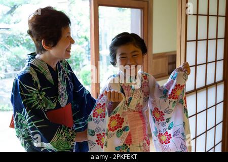 A girl being dressed in a yukata Stock Photo