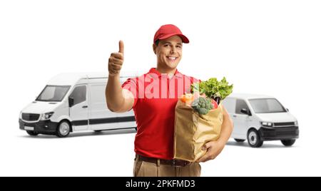 Male courier with a bag of groceries showing thumbs up in front of vans isolated on white background Stock Photo