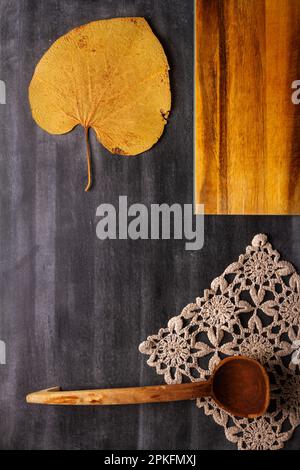 Old cutting board with linen napkin and spoon on black wooden background. Flat lay. Top view. Copy space. Stock Photo