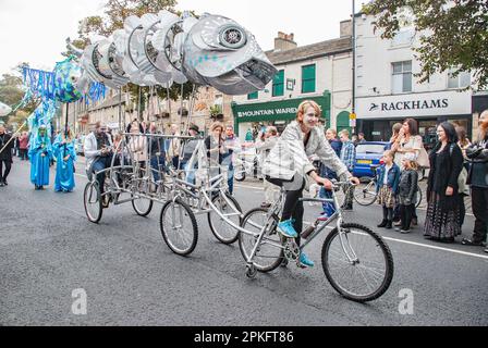 Giant fish is hauled by a cyclist in the street parade at the Skipton International Puppet Festival 2015 Stock Photo