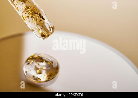 Pipette and gel cosmetic products with gold in a Petri dish on beige background Stock Photo