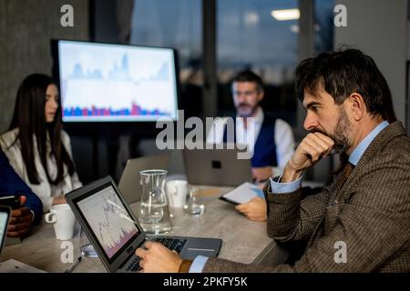 Financial broker analyzes data in the office with colleagues, working late at night Stock Photo