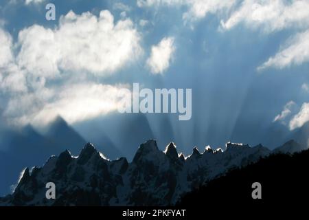 Spectacular sun rise with white clouds in the sky, sun rays cutting off snowy Himalayan mountain peaks. Shot at Lachung, Sikkim, India. Stock Photo