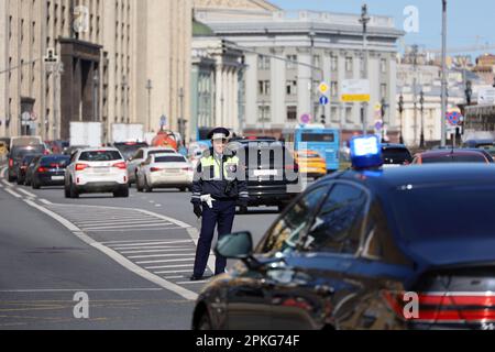 Traffic police officer standing against cars and State Duma building, car with flashing light in foreground. Policeman patrol the city street Stock Photo