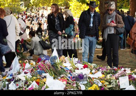 Floral tributes to the late Queen Elizabeth II in Green park, London. UK, with a crowd of people passing by looking Stock Photo