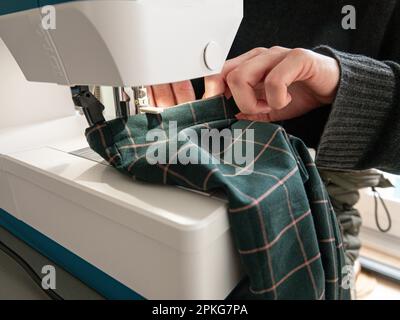 Woman sews a piece of clothing on a modern electric sewing machine. Close up image. Stock Photo
