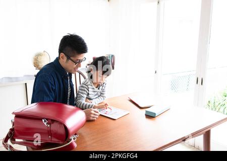 Girl studying with tablet and father helping her Stock Photo