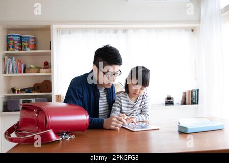 Girl studying with tablet and father helping her Stock Photo