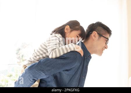 Girl being carried on her back by her father Stock Photo