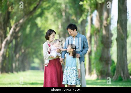 Family smiling at a row of poplar trees Stock Photo