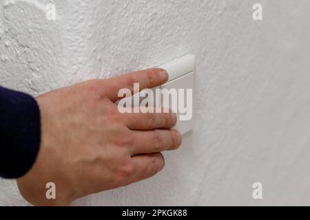 a light switch, a plastic mechanical switch of white color installed on a white wall. Stock Photo