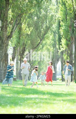 A family of three generations running alongside poplar trees Stock Photo