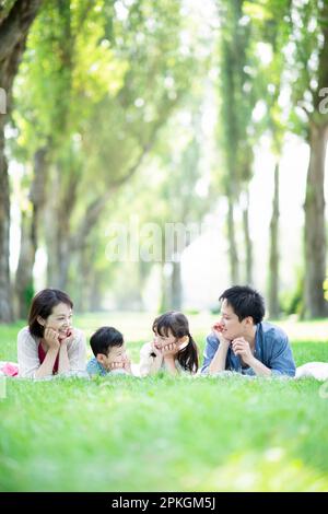 Family lying down on a row of poplar trees Stock Photo