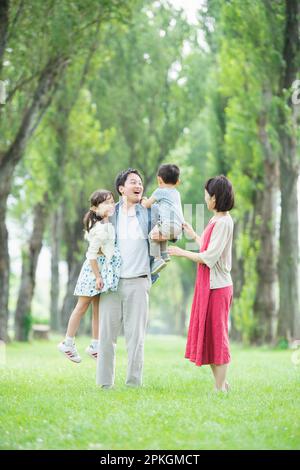 Parent and child playing in a row of poplar trees Stock Photo