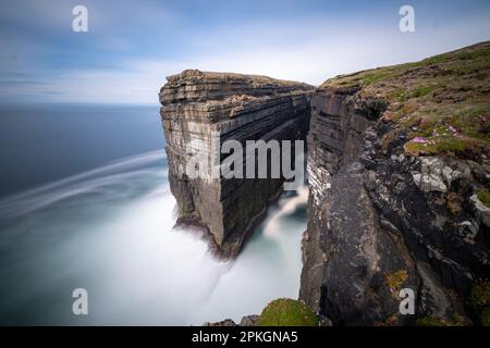 Diarmuid and Grainnes Rock. Long exposure still image during a sunny day with blue sky in the background and sea motion blurred out. Stock Photo