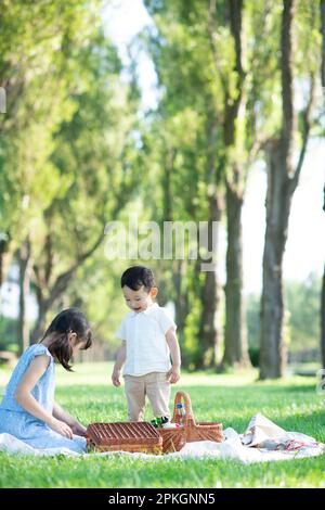 Sister and brother having a picnic at a poplar tree-lined park Stock Photo