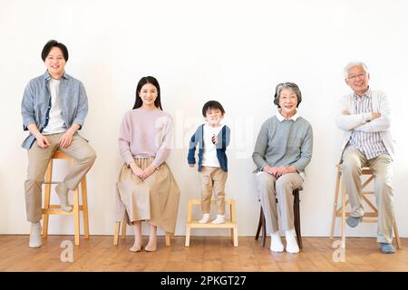Family of 3 generations sitting on a chair and smiling Stock Photo