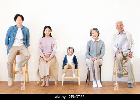 Family of three generations sitting on a chair and smiling Stock Photo