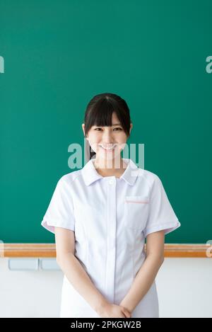 Smiling nursing student in front of the blackboard Stock Photo
