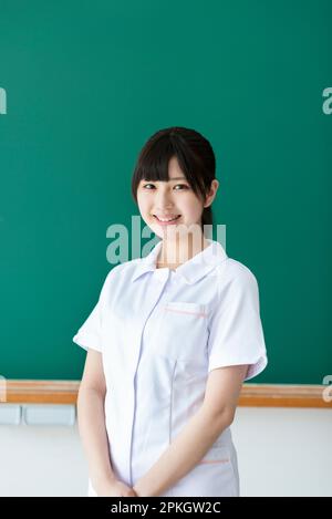 Smiling nursing student in front of the blackboard Stock Photo