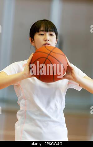 Female student playing basketball in gymnasium Stock Photo