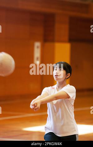 Female students playing volleyball in the gym Stock Photo