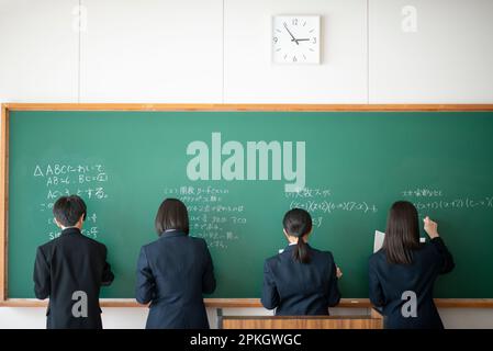 Chalk Writing Answer Back view of a student writing answers on the blackboard with chalk ...