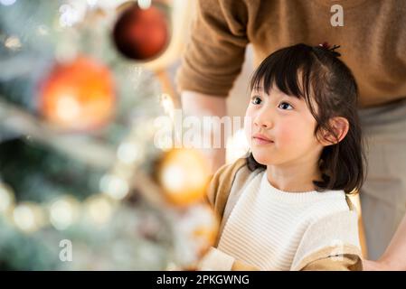 Girl looking up at the Christmas tree Stock Photo