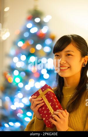 Woman holding a present and smiling in front of the lights Stock Photo