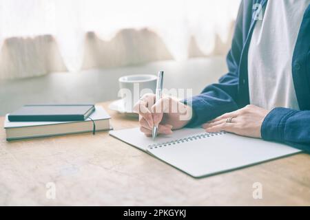 Woman writing notes at a café Stock Photo