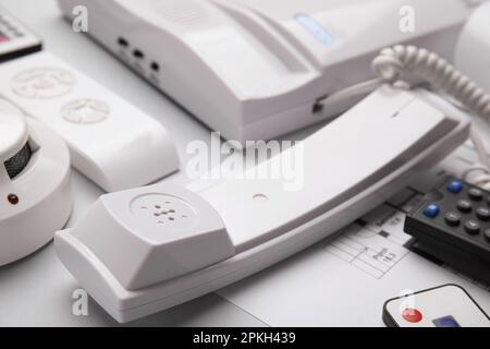 Handset of intercom, smoke detector and remote controls on white background, closeup. Home security system Stock Photo