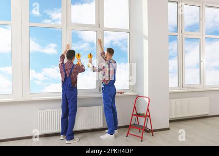 Workers using suction lifters during plastic window installation indoors Stock Photo