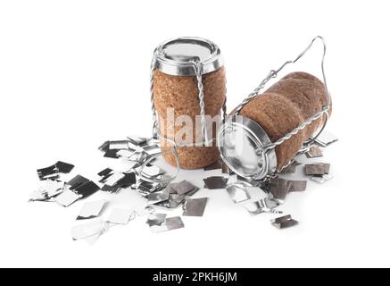 Corks of sparkling wine with muselet caps and shiny silver confetti on white background Stock Photo