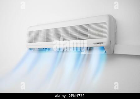 Modern conditioner and illustration of cool air flow on white wall indoors Stock Photo