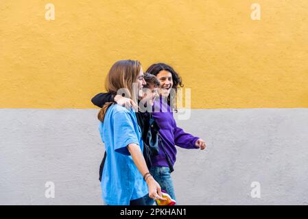 Young diverse friends walking on the street with pride rainbow flag. Stock Photo