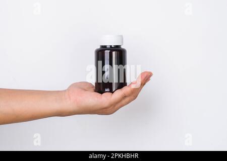 Female hand holding blank pill bottle isolated on white background. Packaging for pill, capsule or supplement with copy space for text. Stock Photo