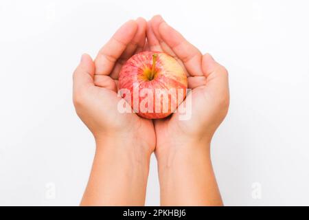 Hand holding red apple isolated on white background. Ripe red apple in human hand. Stock Photo