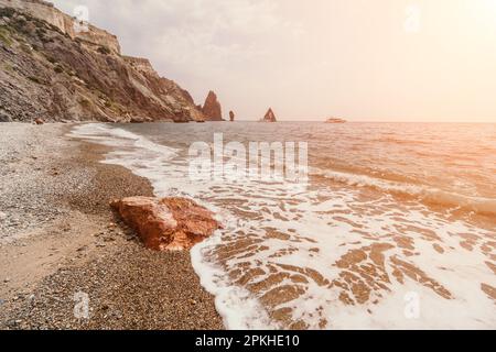 Large red jasper rock on the beach, with the sea in the background. Big Red Jasper Stone Close Up Stock Photo