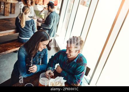 We just get each other. a young couple having drinks in a bar with people blurred in the background. Stock Photo