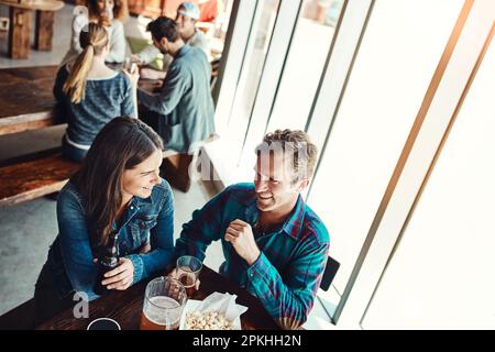 Were not the stay-in kinda couple. a young couple having drinks in a bar with people blurred in the background. Stock Photo